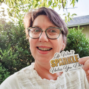 Susan holding Life Won't Sparkle Until You Do! sticker